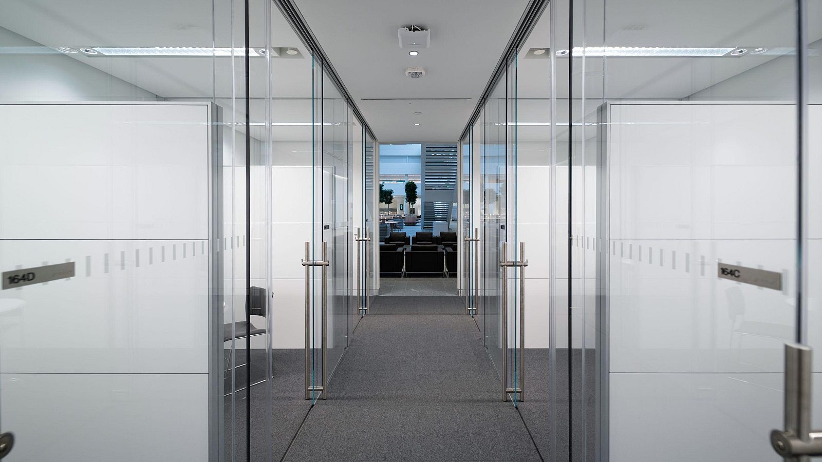 A hallway with glass walls on both sides, showing thin joins and floor and ceiling tracks.