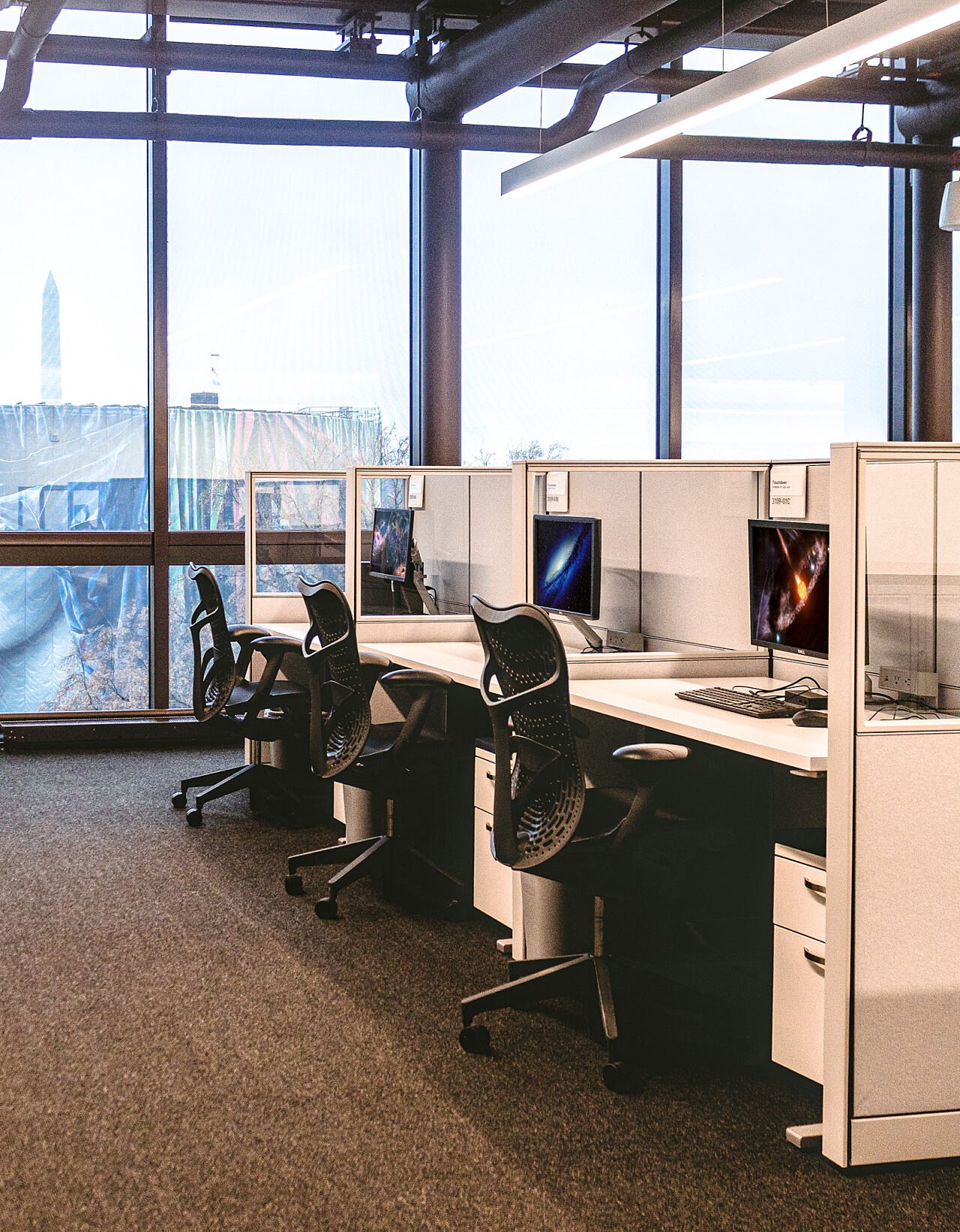 A cluster of small workstations with fabric and glass panels separating them