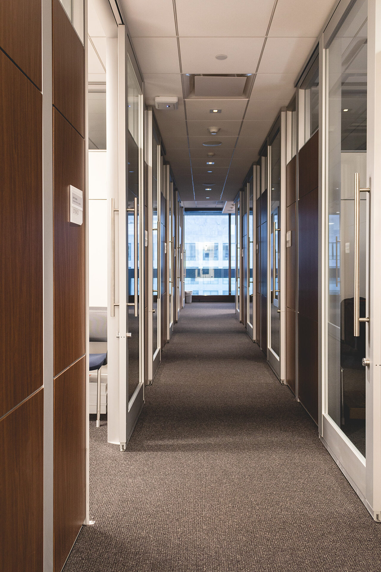 A hallway of rooms with glass and wood modular walls