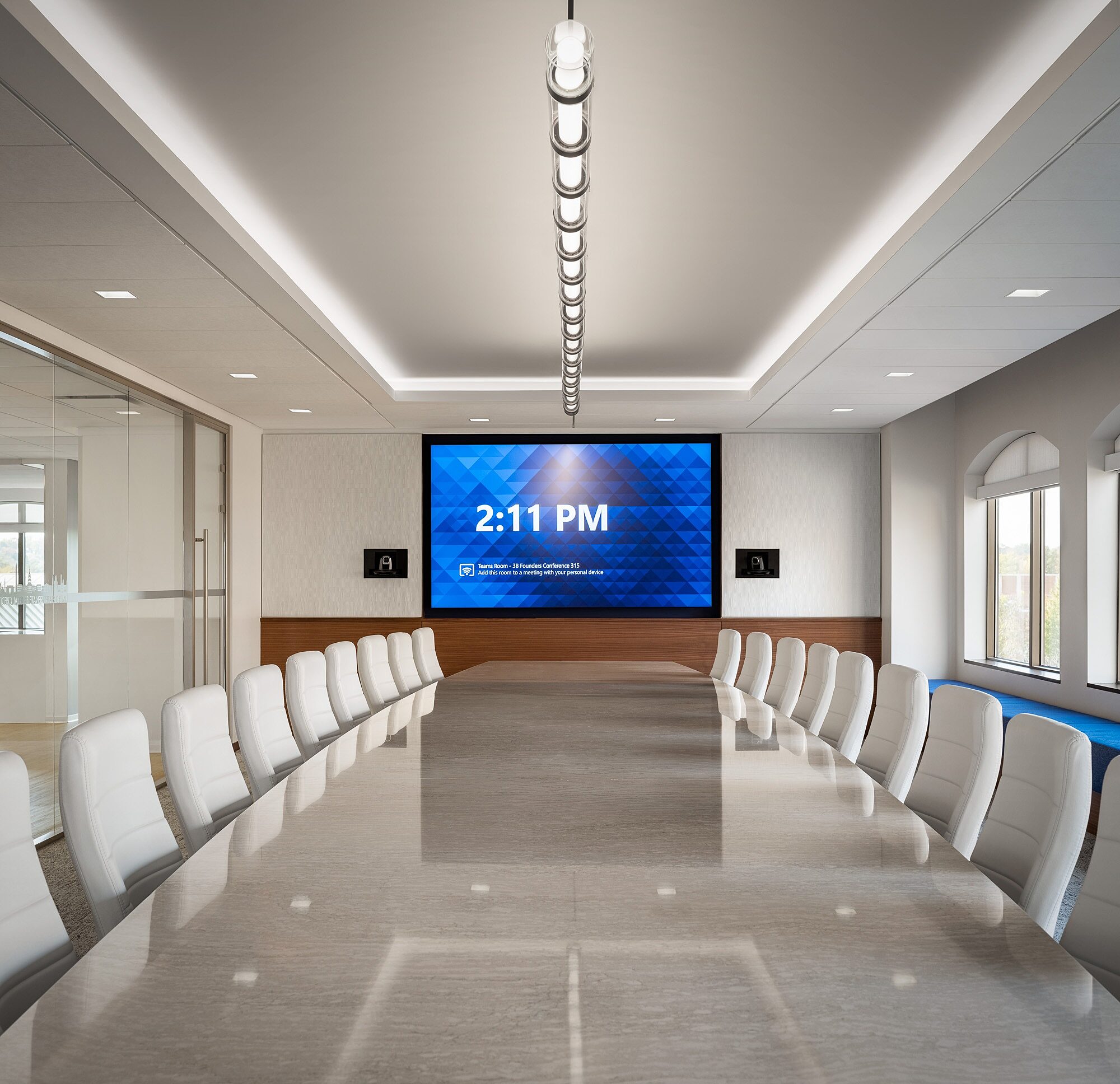 A conference table with seats to either side and a tv at the far end