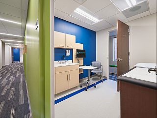 An examination room with cabinets, chair, and mobile table